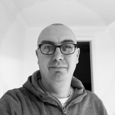 A black and white selfie of a man wearing glasses and a hoodie.